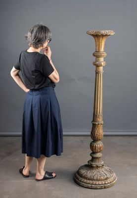 a woman that is standing next to a tall vase