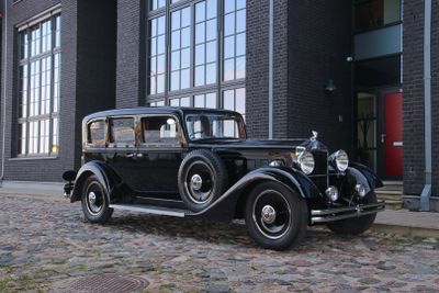 a old black car parked in front of a building