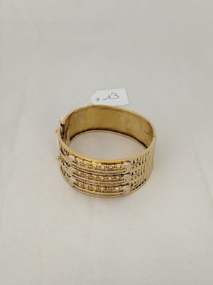 a close up of a gold bracelet on a white surface