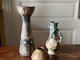 trois vases posés sur une table en bois devant une porte