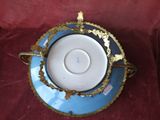 une tasse et une soucoupe bleues et dorées posées sur un napperon rouge