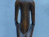 wooden statue of a man sitting on a pedestal with a hat on his head