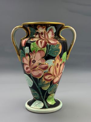 un vase avec des fleurs peintes dessus, posé sur une table