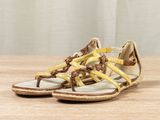 yellow and brown sandals on a wooden table with a curtain in the background