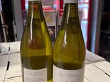 two bottles of white wine sitting on a table