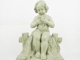 a small statue of a child sitting on a bench