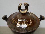 a brown pot that has a bird on top of it