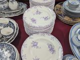 de nombreuses assiettes et bols posés sur une table, avec une horloge en arrière-plan