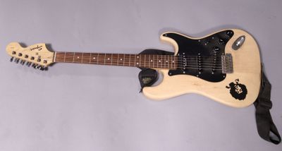 an electric guitar is laying on a white surface with a black strap around it