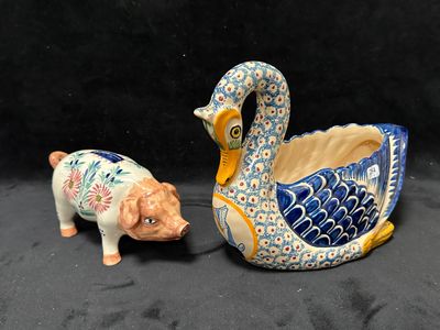 deux figurines en céramique représentant un cochon et un cygne sur fond noir
