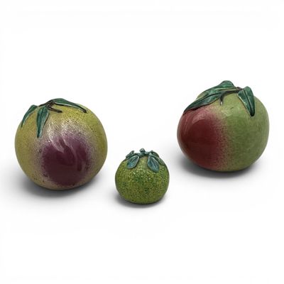 three tomatoes and two pears on a white surface