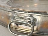 a silver plate with a metal handle on a table