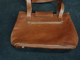 brown leather handbag sitting on a blue carpeted floor
