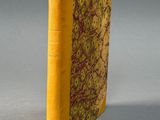 an old book with a yellow cover sitting on top of a table