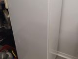 un réfrigérateur blanc et des toilettes dans une petite pièce