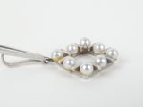 silver and white pearled broocher on a white background
