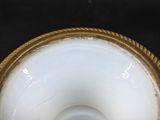 a white vase with a gold rim on a black table