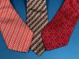 three different colored ties on a blue surface with a blue background