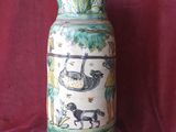 a vase with a picture of animals on it on a red cloth