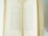 someone is holding a book open in their hand on a white surface