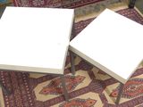 two tables that are sitting on a rug on the floor