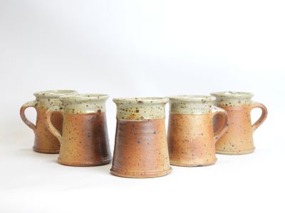 three brown and white mugs sitting next to each other on a white surface
