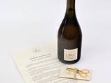 une bouteille de vin posée sur une feuille de papier, à côté d'une paire de ciseaux