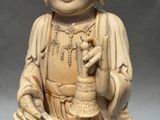 une statue représentant une personne tenant une cloche à la main