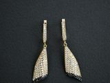 a pair of gold and diamond earrings on a black background
