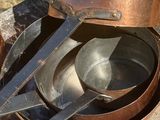 Des casseroles et des poêles sont posées sur un rocher à l'extérieur, par une journée ensoleillée.