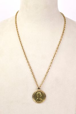 un collier en or avec une pièce de monnaie sur le cou d'un mannequin