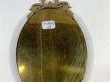 a gold oval mirror hanging on a white wall