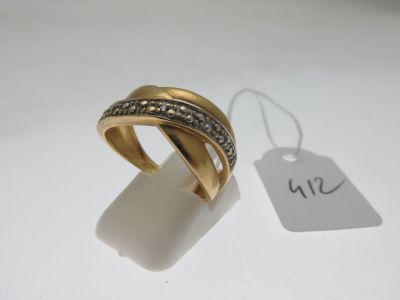 gros plan d'une bague en or avec des diamants sur une surface blanche