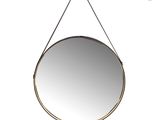 a round mirror hanging on a wall with a rope