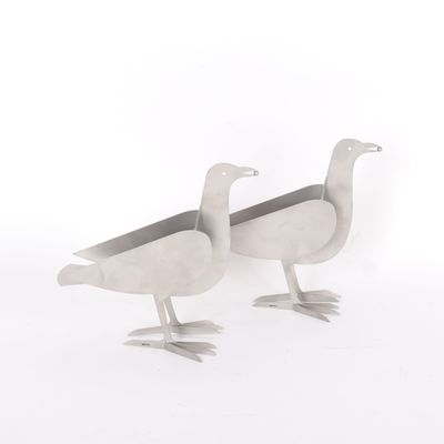 Il s'agit de deux oiseaux en métal placés l'un à côté de l'autre sur une surface blanche.