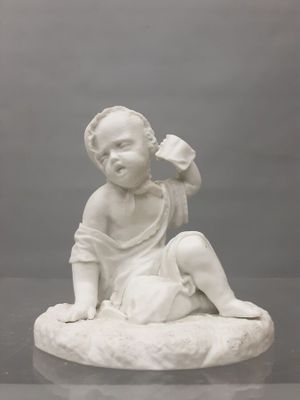 une statue blanche représentant un bébé assis sur un rocher