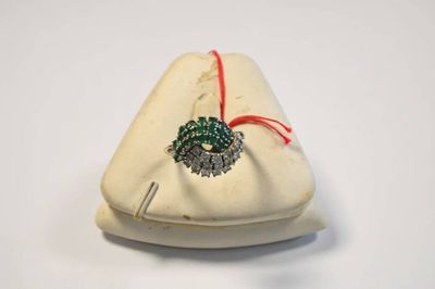 un petit sac blanc orné d'une broche verte