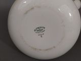 a small white bowl with a handle sitting on a table