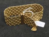 gros plan d'un bracelet en or sur une surface noire
