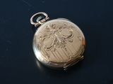 a gold pocket watch sitting on a black surface