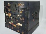 une petite boîte noire sur laquelle sont peints des fleurs et des feuilles