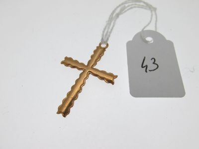 une croix en or et une étiquette de prix posées sur une table blanche