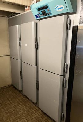 a row of refrigerators in a kitchen with a clock on the top