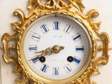 a gold clock sitting on top of a white table