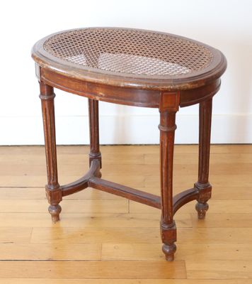 a small wooden table with a woven top on a hard wood floor