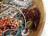 a wooden bowl filled with assorted jewelry on a table
