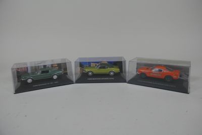 trois modèles de voitures différents exposés dans une vitrine posée sur une surface blanche