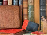 many books on a shelf next to a box and a candle