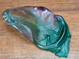 a green leaf shaped glass dish on a wooden table