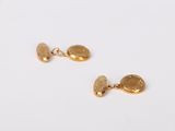 two gold earrings on a white surface with a white background